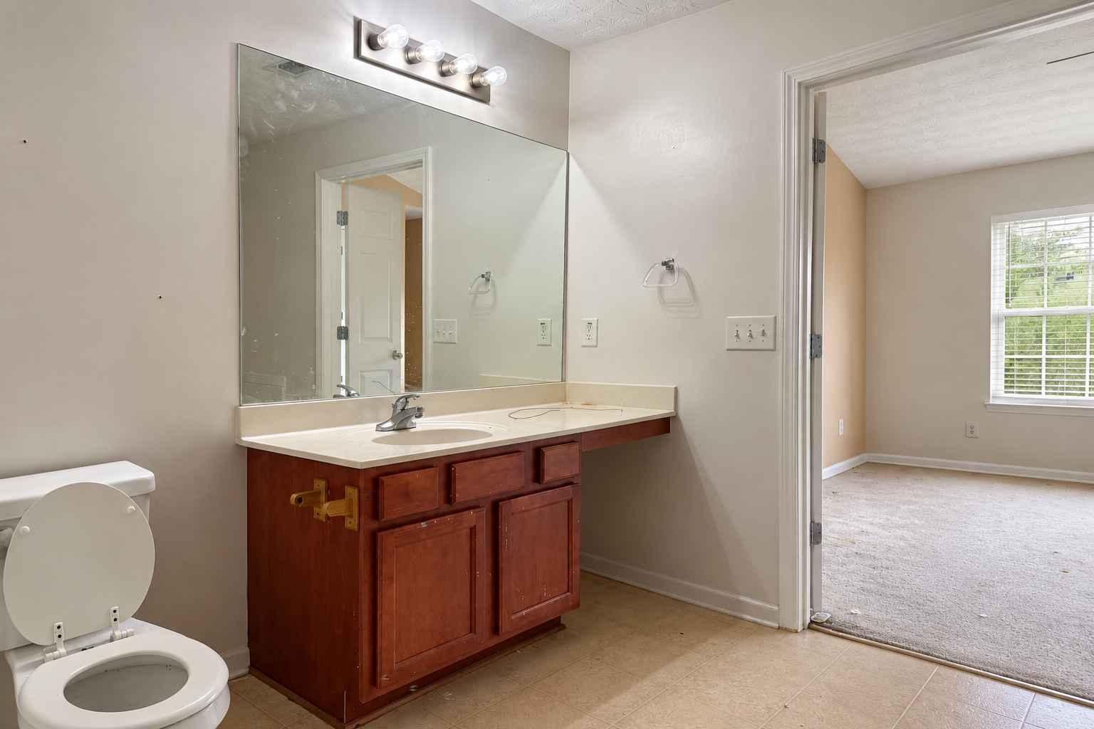 Bathroom before renovation with dark wood vanity, old countertop and tile flooring