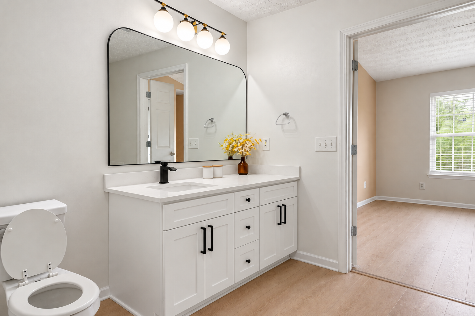 Modern bathroom after renovation with white vanity, quartz countertop and wood-look flooring
